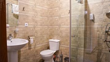 Un baño con lavamanos, inodoro y cabina de ducha de vidrio.