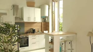 Une cuisine moderne avec des meubles blancs, un îlot central et un luminaire suspendu.