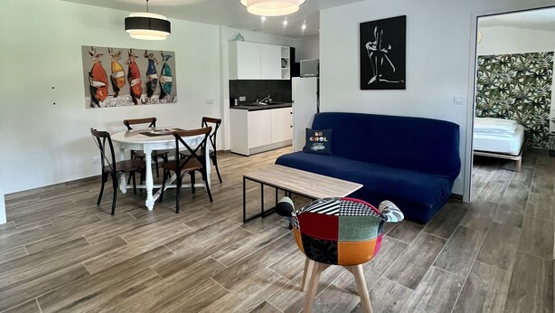 A modern living room with a blue sofa, a dining table with chairs, and a colorful ottoman. - House in a very quiet area (Saint-Georges-d'Oléron)