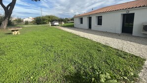 A white building with a tiled roof, a gravel driveway, and a grassy lawn. - House in a very quiet area (Saint-Georges-d'Oléron)