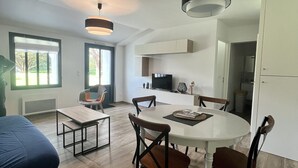 A modern living room with a dining area, wooden flooring, and a large window. - House in a very quiet area (Saint-Georges-d'Oléron)