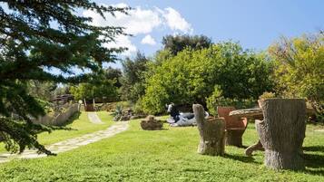 Un jardín con una vaca, un banco de piedra y un tocón de árbol.