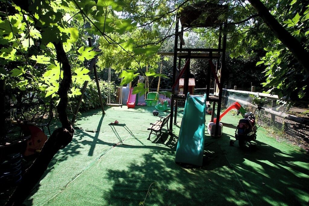 A playground with green artificial turf, a swing set, and a slide.
