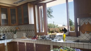 A kitchen with wooden cabinets, a tiled backsplash, a window with a view of the outside, and a sink. - Villa Chorisia. Antique furniture Villa, large rooms and quiet area (Messina)