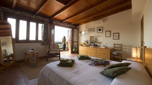 A bedroom with a large bed, wooden ceiling beams, a dresser, and a window with curtains. - Villa Chorisia. Antique furniture Villa, large rooms and quiet area (Messina)
