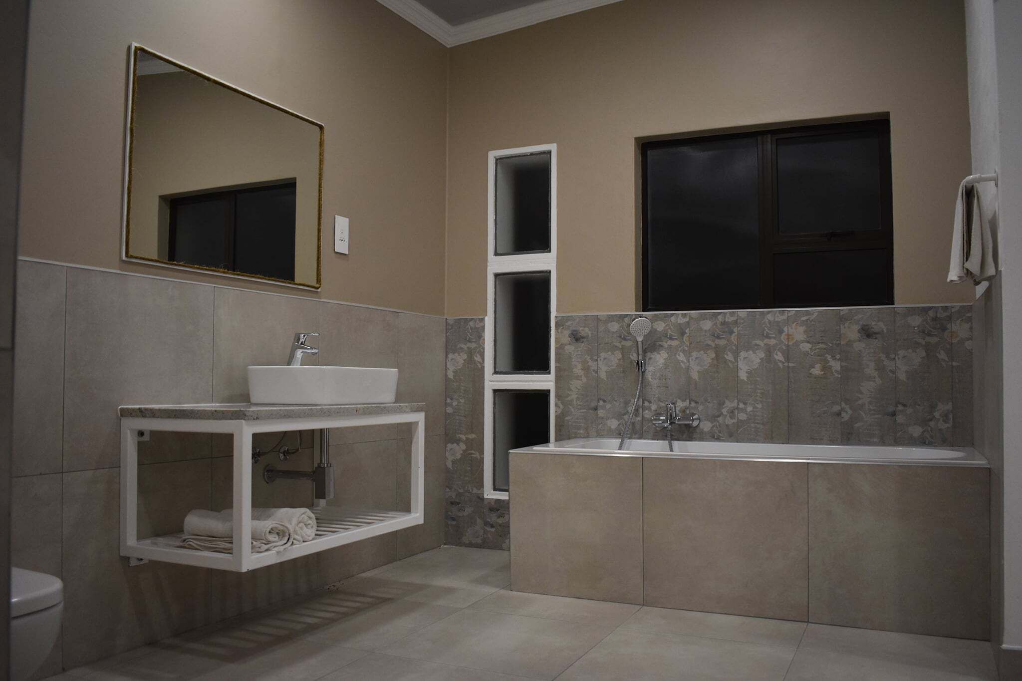 A modern bathroom with a large bathtub, a sink with a marble countertop, and a mirror above the sink.