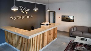 Ett väntrum med en receptionsdisk i trä, två hängande lampor, en soffa och ett soffbord.