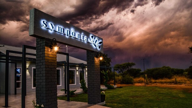 En hotellentrél med en skylt som visar texten ”Sympónia Spa” under en dramatisk himmel.