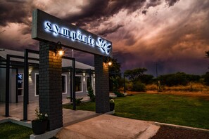 A hotel entrance with a sign reading "Sympónia Spa" under a dramatic sky.