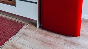 Keittiössä on punainen jääkaappi, mikroaaltouuni ja liesi.