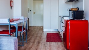 Kompakti oleskelutila, jossa on pieni keittiö, ruokailualue pöytineen ja tuoleineen sekä sohva.