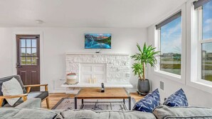 A modern living room with a white fireplace, a large window, and a view of the outdoors.
