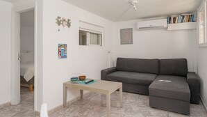 Una sala de estar con un sofá gris, una mesita y un ventanal.