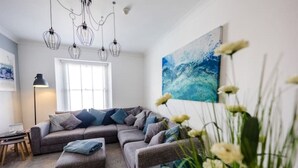 A modern living room with a sectional sofa, a floor lamp, and a large abstract painting.