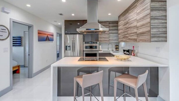 A modern kitchen with a central island, stainless steel appliances, and a sleek design. - Retreat Near MIA • Playground & Heated Pool, BBQ (Miami)