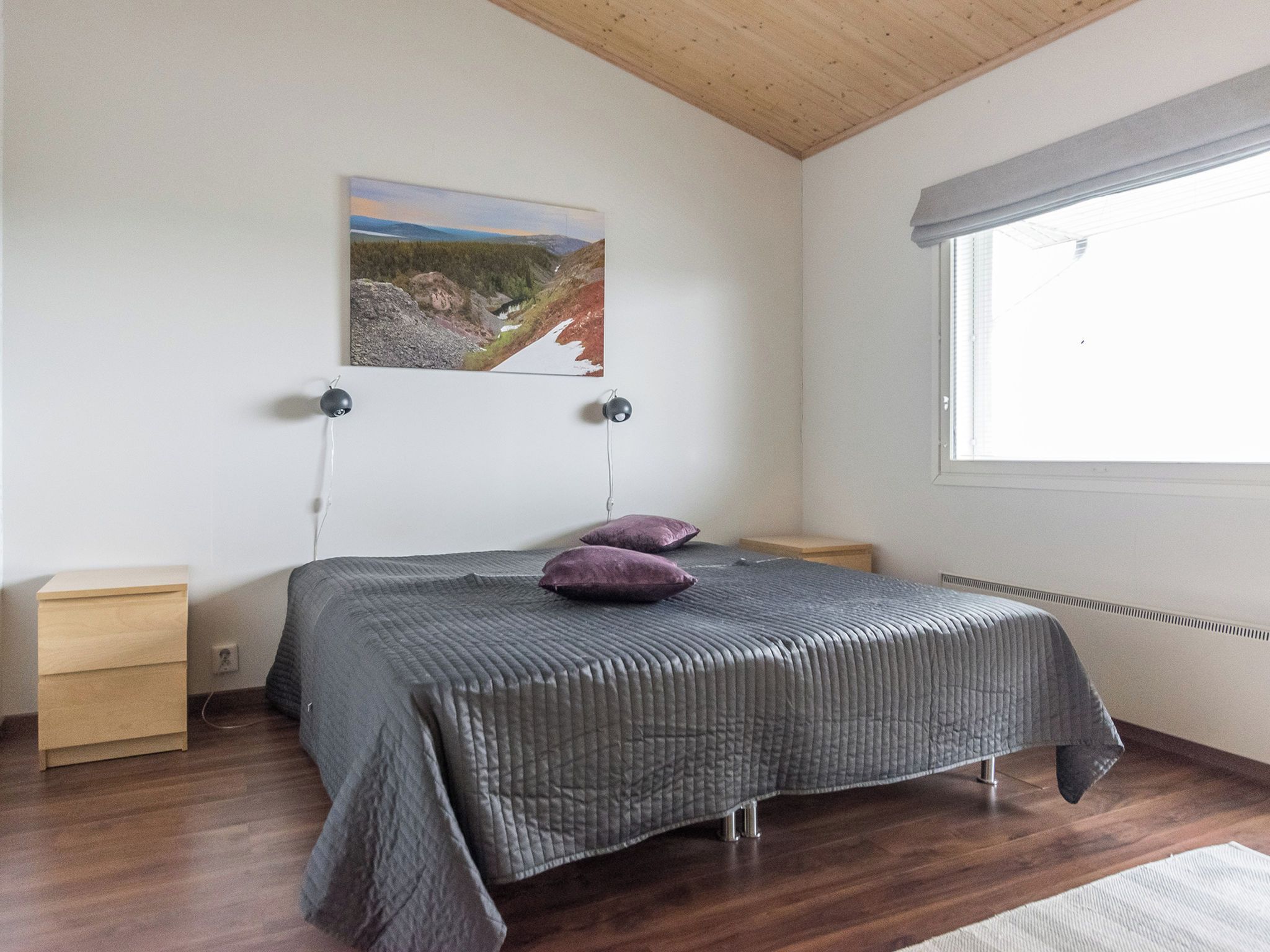 Ein Schlafzimmer mit einem Bett, zwei Nachttischen, einem Fenster und einem Bild an der Wand.