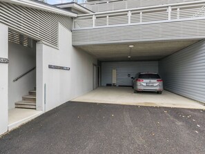 A parking garage with a car parked inside. There is a staircase leading to a door marked with the number 13.