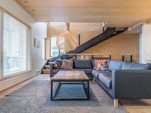 Een moderne woonkamer met een bank, salontafel en een trap.