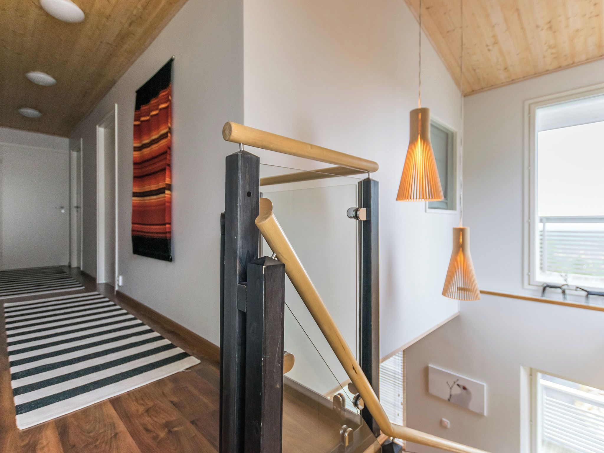 Ein modernes Interieur mit Holzboden, einem schwarz-weißen Streifen Teppich und einer hölzernen Kletterkonstruktion.