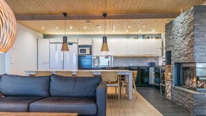 Een moderne woonkamer met een bank, eettafel en een open haard.