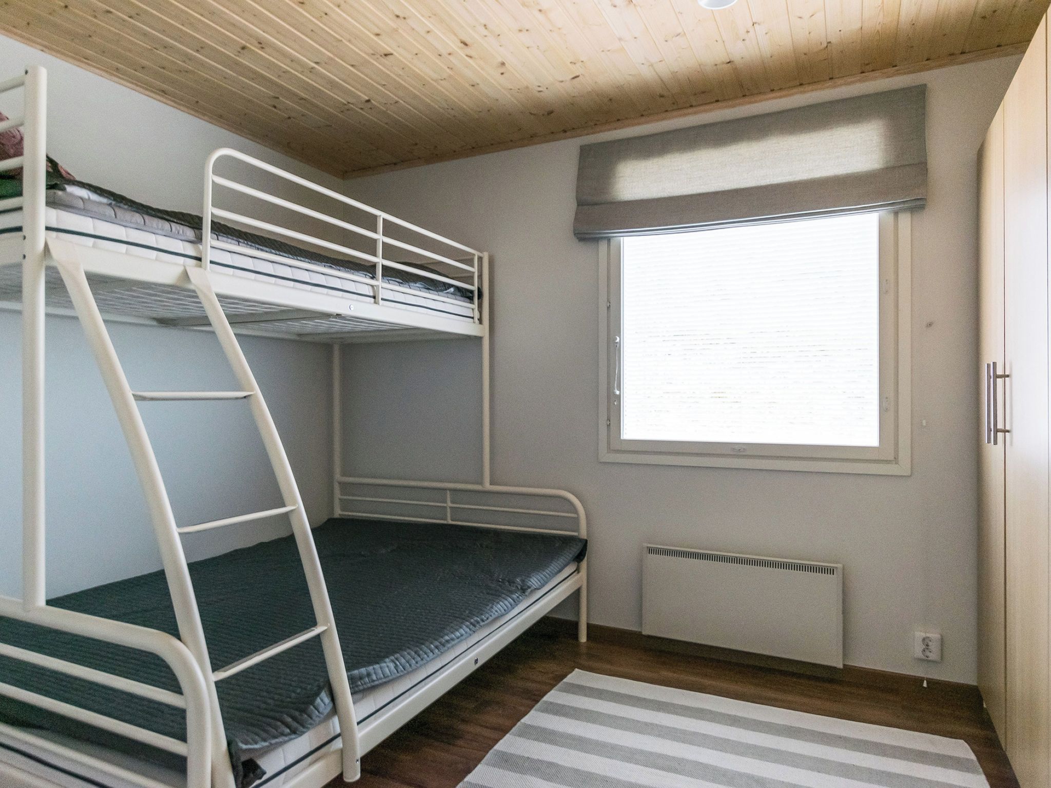 Habitación con literas, ventana y radiador.