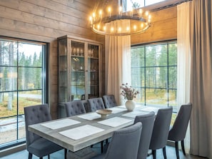 Een eetgedeelte met een grote tafel, stoelen en een kroonluchter.
