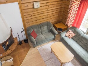 A cozy living room with a fireplace, two sofas, a coffee table, and a clock on the wall. - Kranni 2 by Interhome (Pudasjärvi)