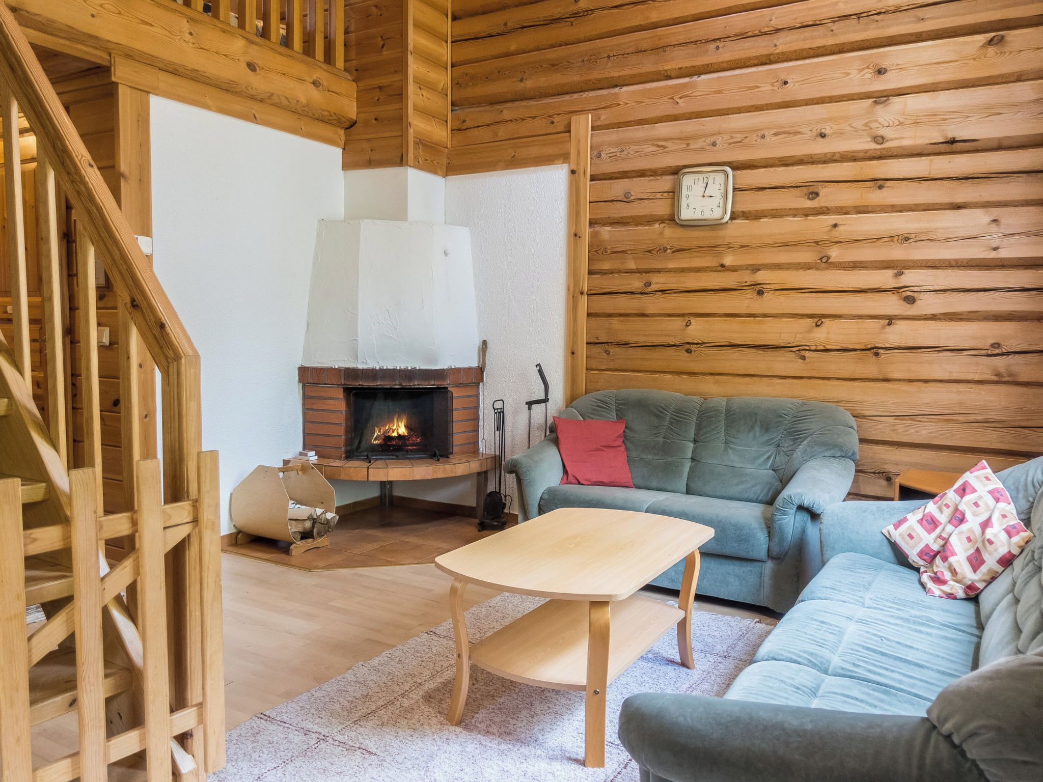 Ein gemütliches Blockhaus-Interieur mit einer Holztreppe, einem Kamin, einer Couch und einem kleinen Tisch.