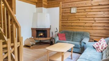 Ein gemütliches Blockhaus-Interieur mit einer Holztreppe, einem Kamin, einer Couch und einem kleinen Tisch.