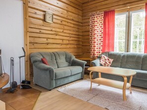 A cozy room with a grey sofa, a wooden table, and a clock on the wall. - Kranni 2 by Interhome (Pudasjärvi)