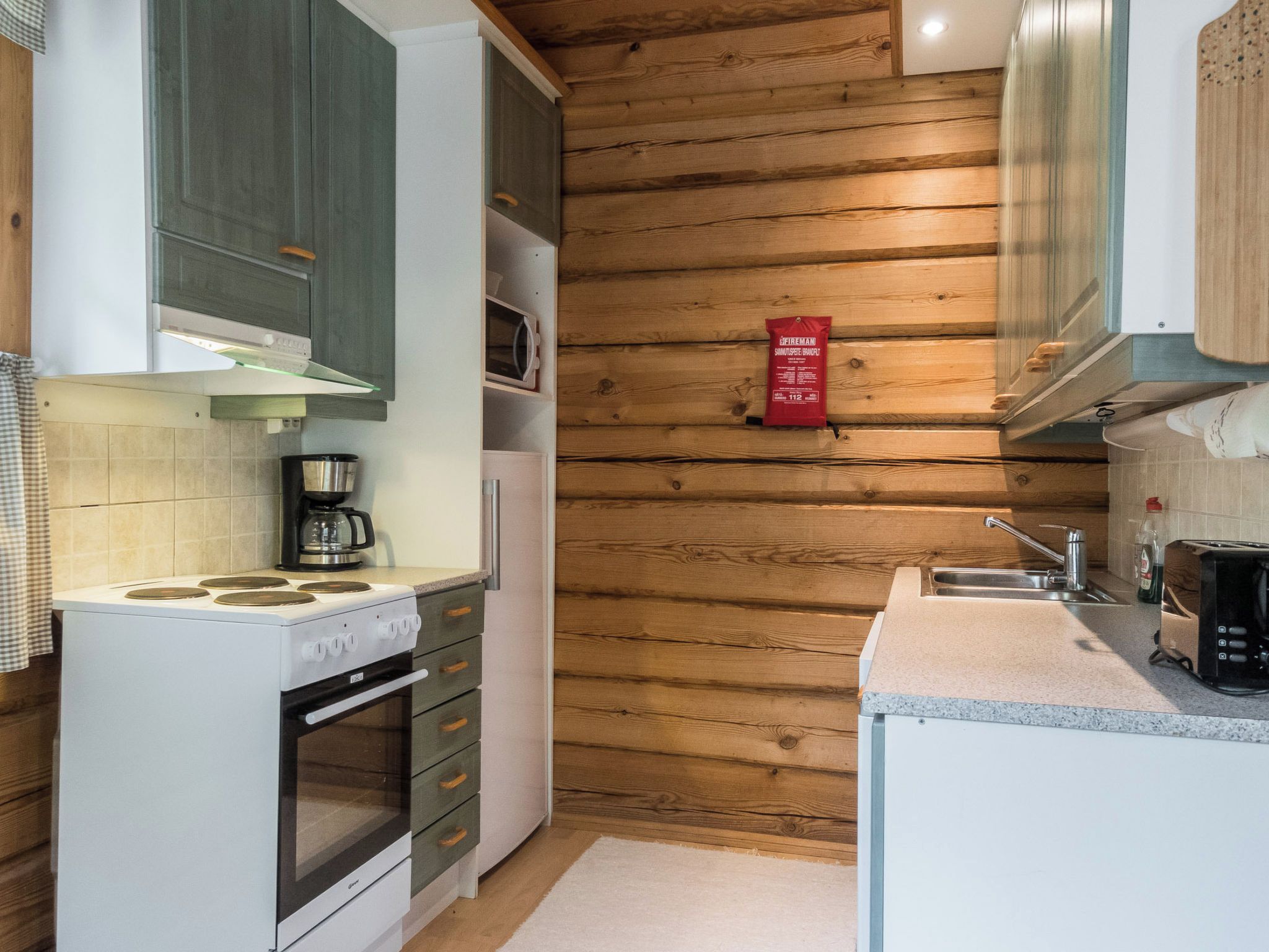 A compact kitchen with a stove, oven, and a coffee maker.