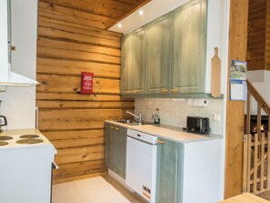 A compact kitchen with wooden walls, a built-in dishwasher, and a toaster. - Kranni 2 by Interhome (Pudasjärvi)