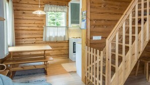 A wooden cabin interior with a dining area, a staircase, and a kitchen. - Kranni 2 by Interhome (Pudasjärvi)