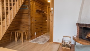 A log cabin interior with a wooden staircase, a fireplace, and a small seating area. - Kranni 2 by Interhome (Pudasjärvi)