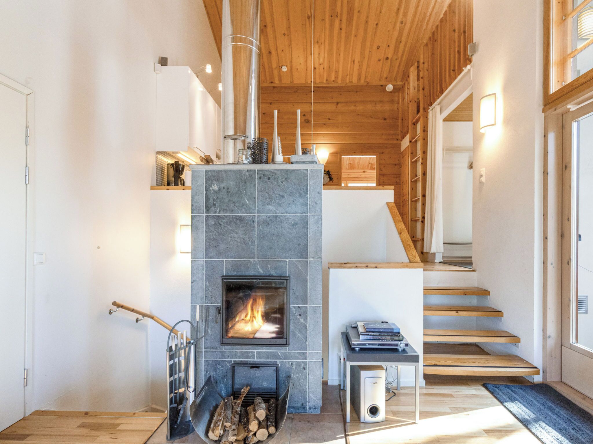 Un interno moderno con camino in pietra, scala in legno e un design minimalista.