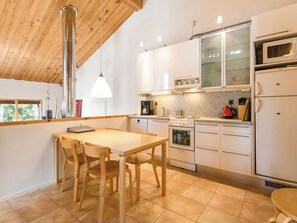 A modern kitchen with wooden cabinets, a dining table with chairs, a stove, a microwave, and a refrigerator. - Sallan lumous b by Interhome (Salla)