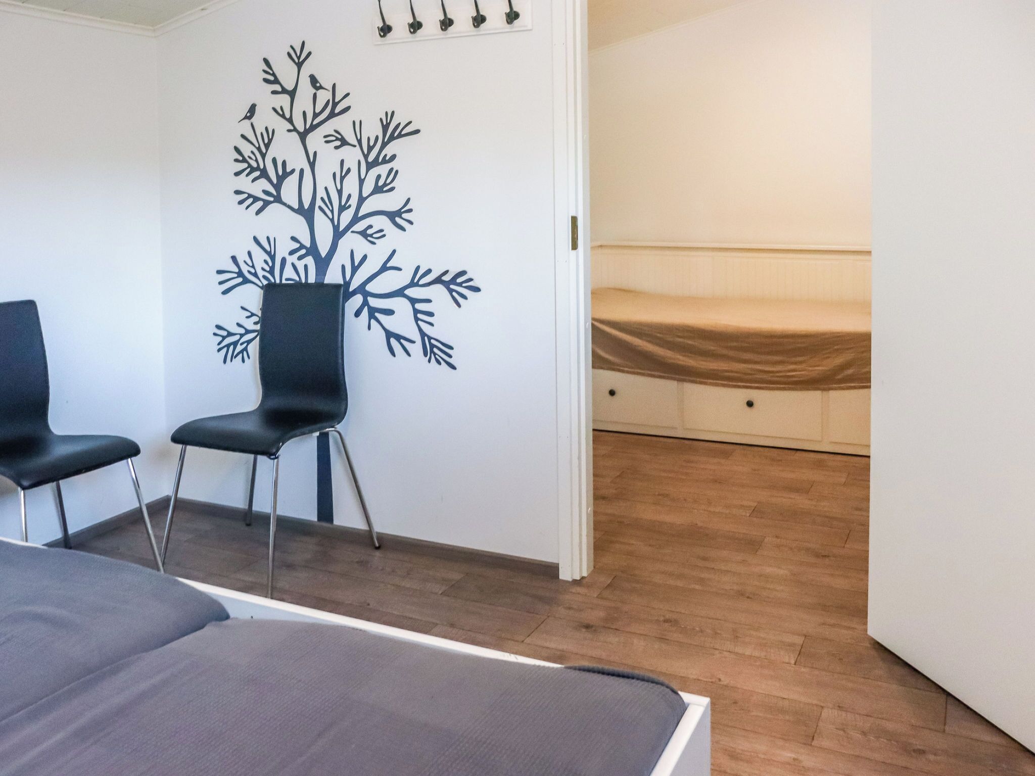 A room with a bed, a chair, a wall-mounted shelf, and a bed with a mattress on the floor.