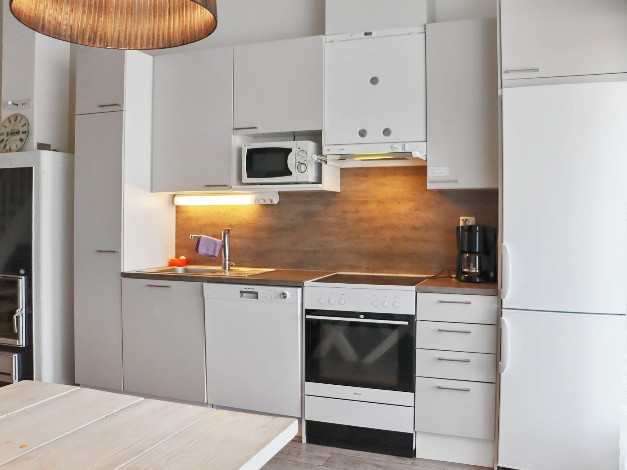 Een koelkast, een magnetron, een vaatwasser, kookgerei, borden en bestek