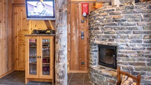 A cozy room with a stone fireplace, wooden cabinets, and a television mounted on the wall.