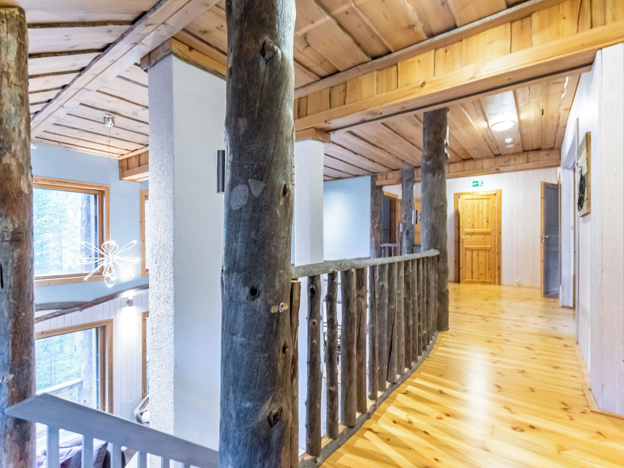 A wooden interior with a high ceiling, a wooden floor, and a railing along the balcony.