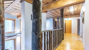 Interior de madera con suelo de madera, barandilla y una puerta al fondo.