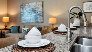 A kitchen with granite countertops, a stainless steel sink, and a modern faucet. - Lovely Family Home | 8-10 min to Disney (Kissimmee)