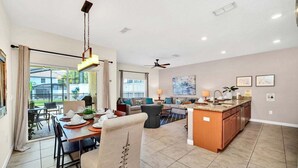 A spacious living area with a dining table, sofa, and kitchen island. - Lovely Family Home | 8-10 min to Disney (Kissimmee)