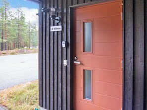 A building with a wooden exterior, a red door, and a sign indicating the number 2.