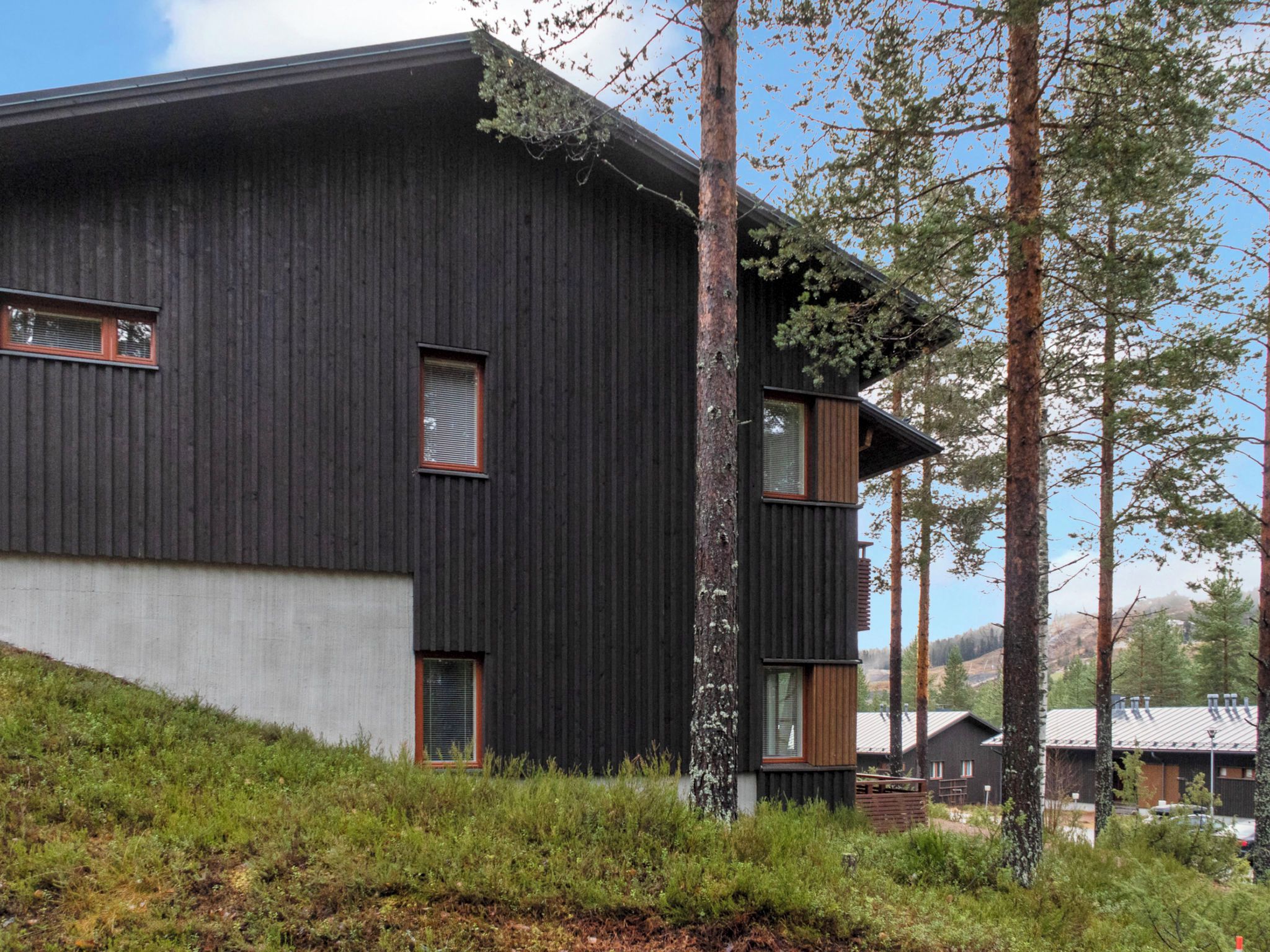 Un bâtiment moderne à l’extérieur sombre, doté de grandes fenêtres et d’un toit en pente.