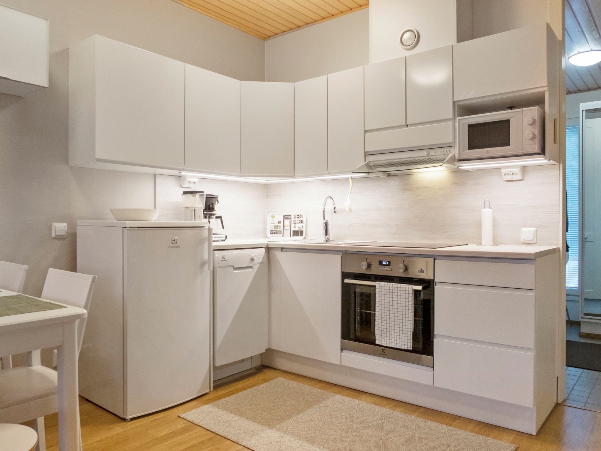 A compact kitchen with white cabinetry, a built-in oven, a microwave, and a dishwasher.