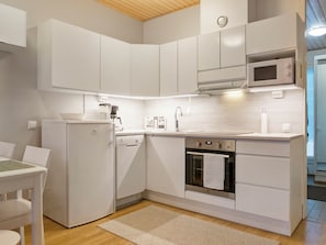 A compact kitchen with white cabinetry, a built-in oven, a microwave, and a dishwasher.