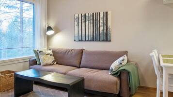 En stue med sofa, sofabord, lampe og et billede på væggen.