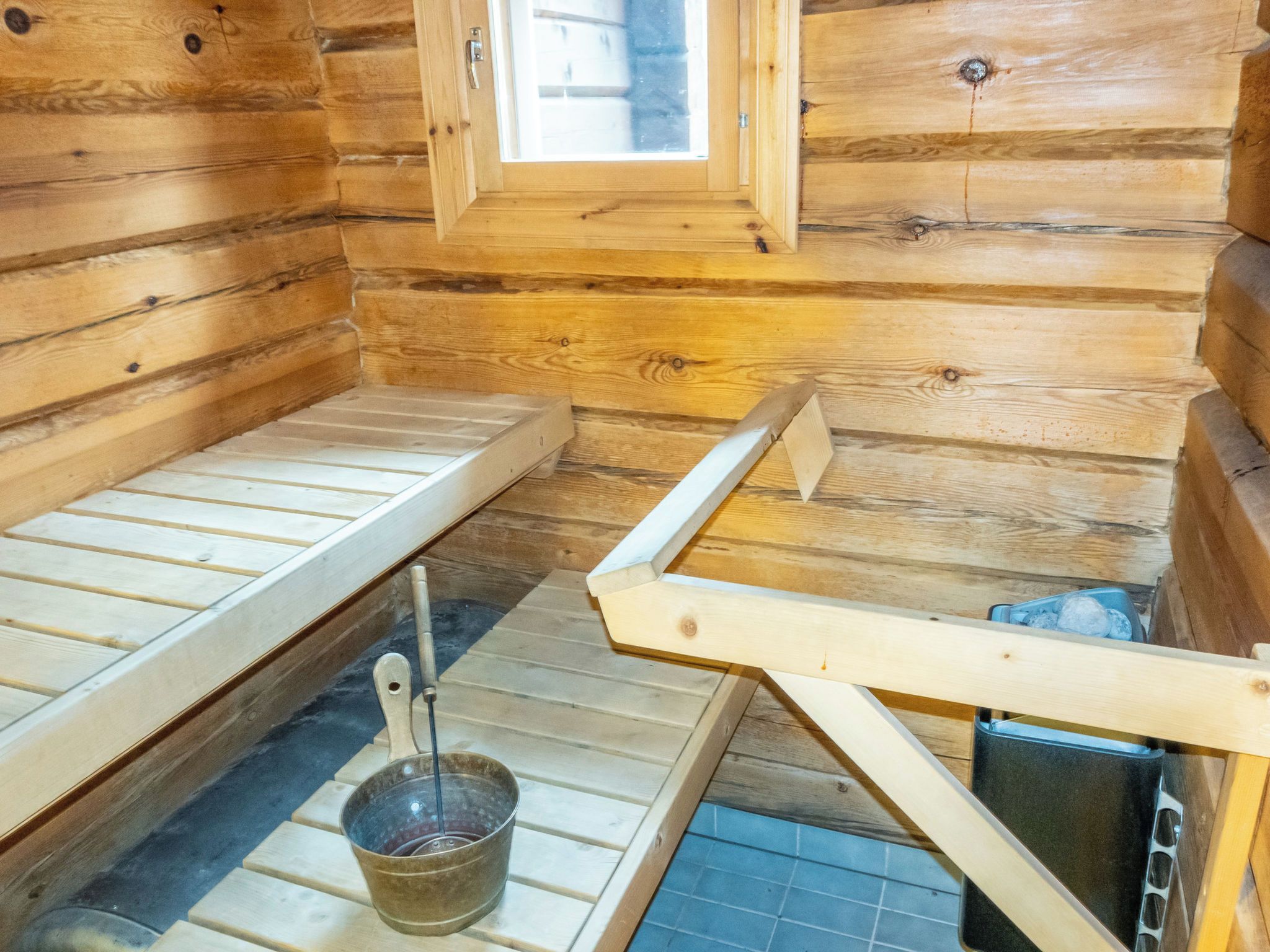 Eine Holzhütte mit zwei Betten aus Holz, einem Fenster und einem Eimer.