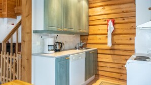 A compact kitchen with wooden walls, a built-in dishwasher, and a stove.
